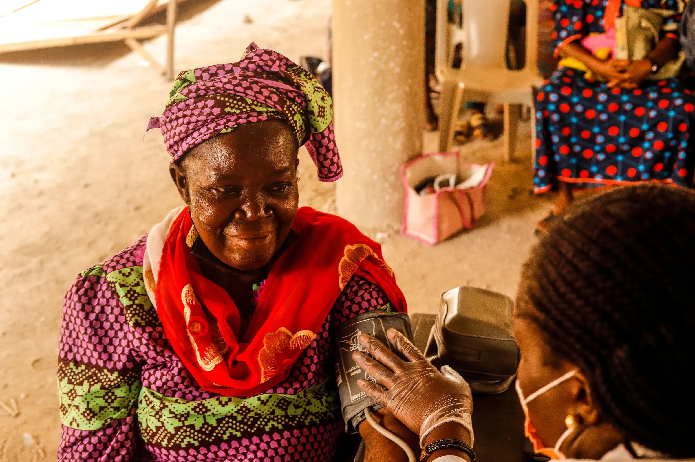 A health worker checks the blood pressure of a smiling elderly woman