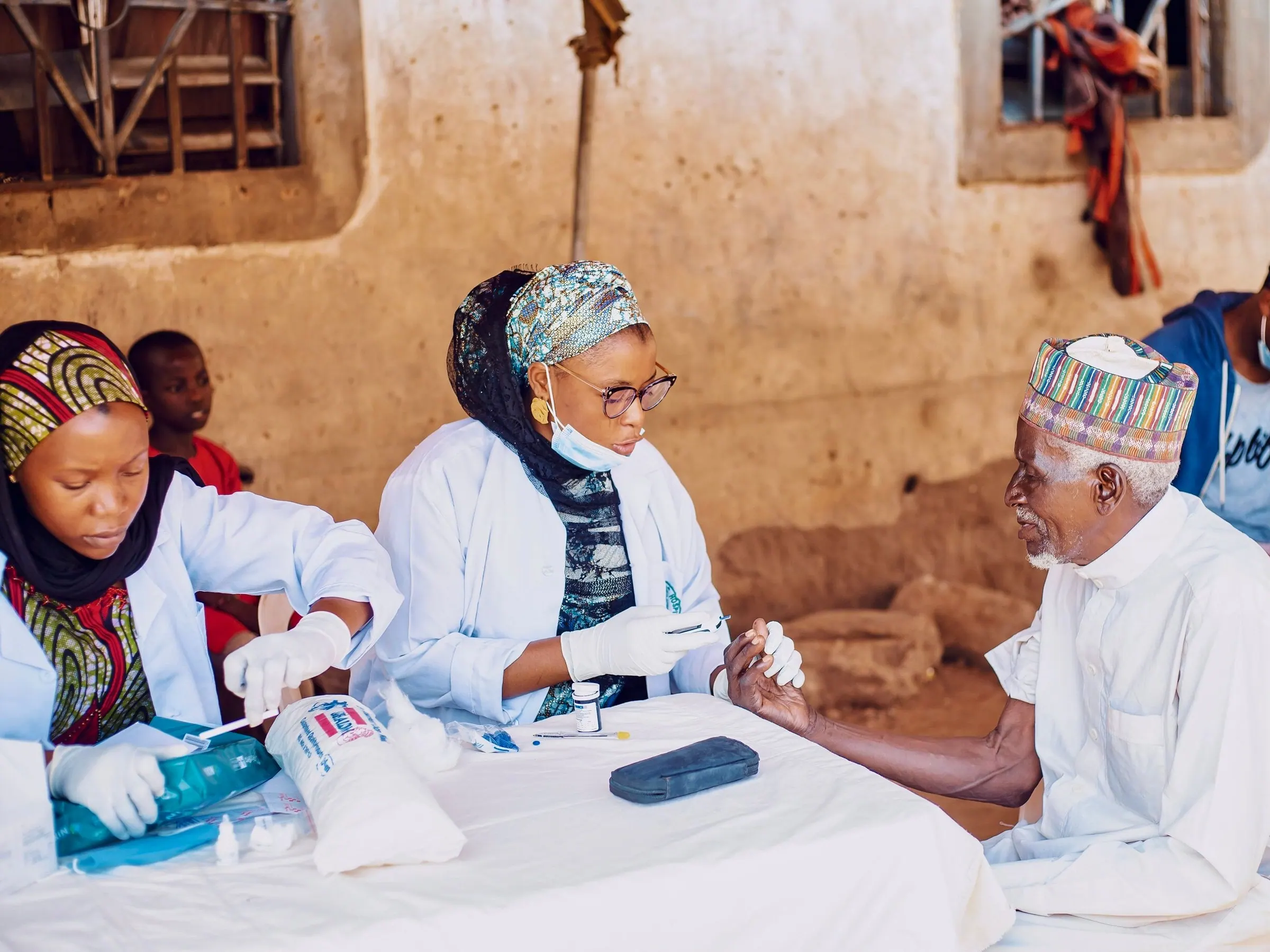 Health workers attending to an elderly man at a community outreach