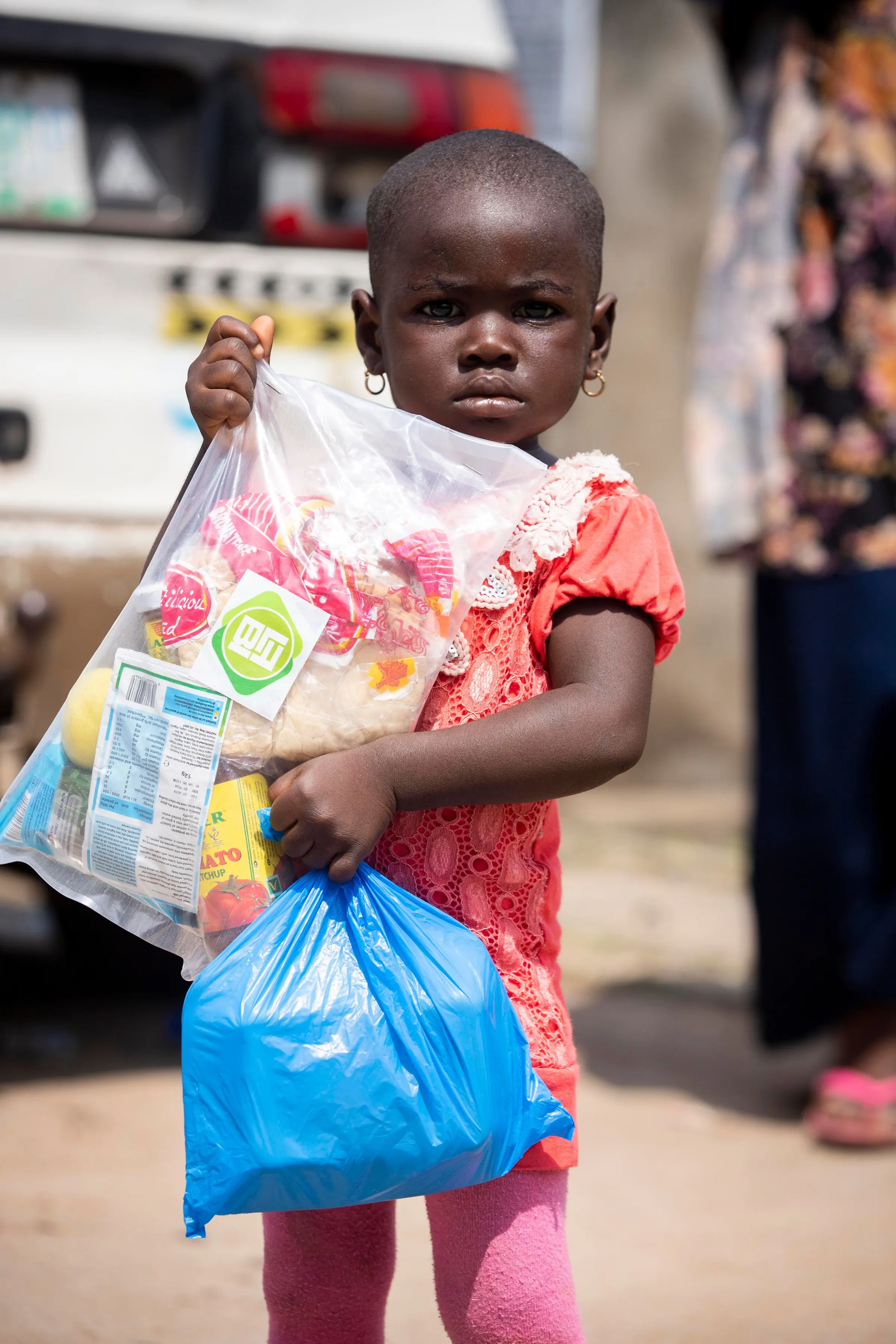 A young girl holding bags of relief supplies