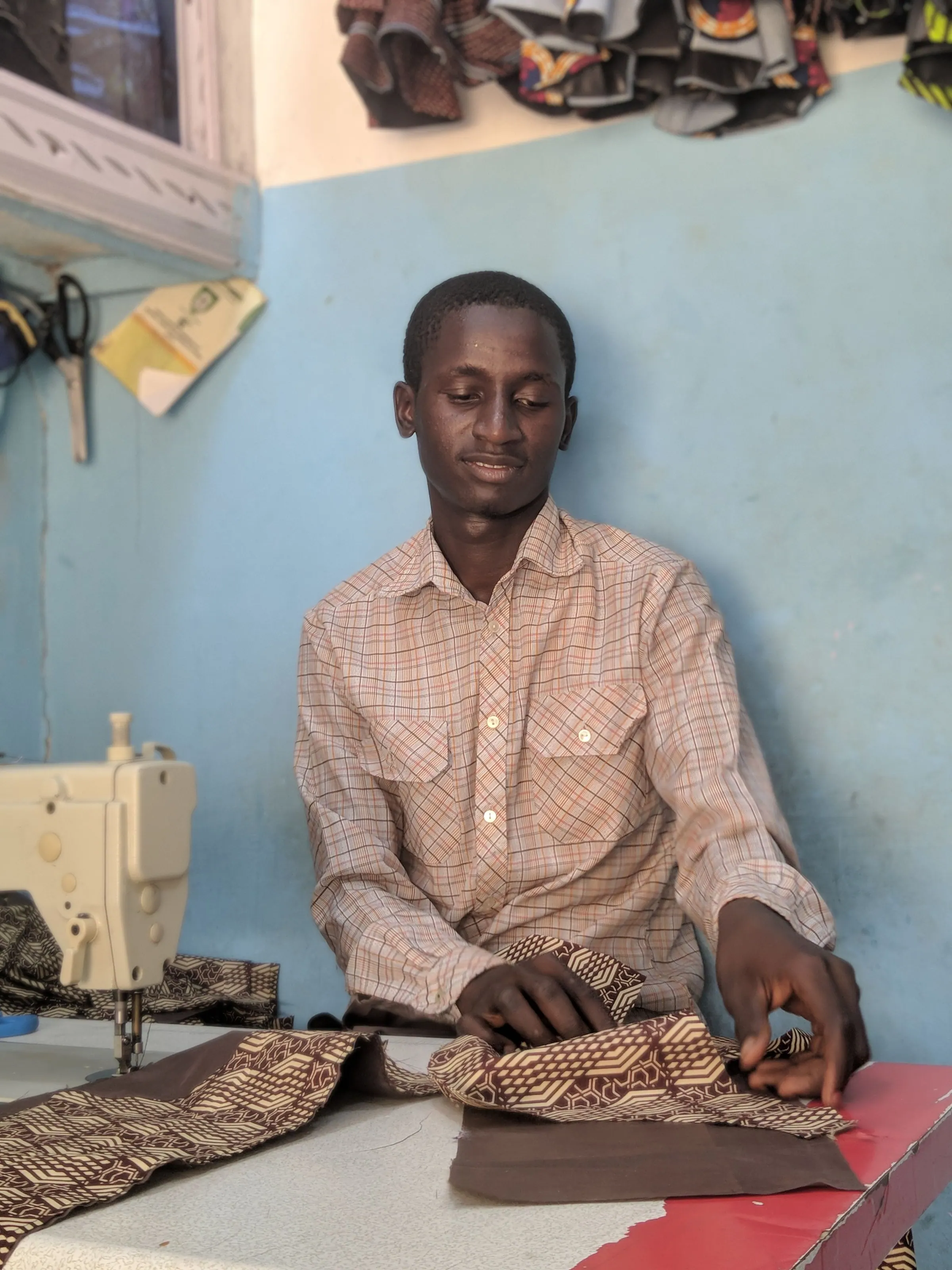 A young tailor working at a sewing machine in his shop